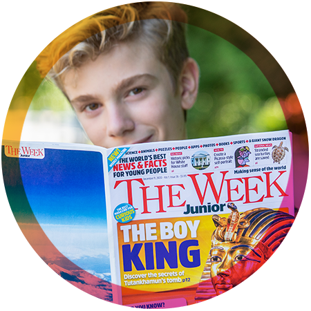 A boy looking over the edge of an issue of The Week Junior with a smile